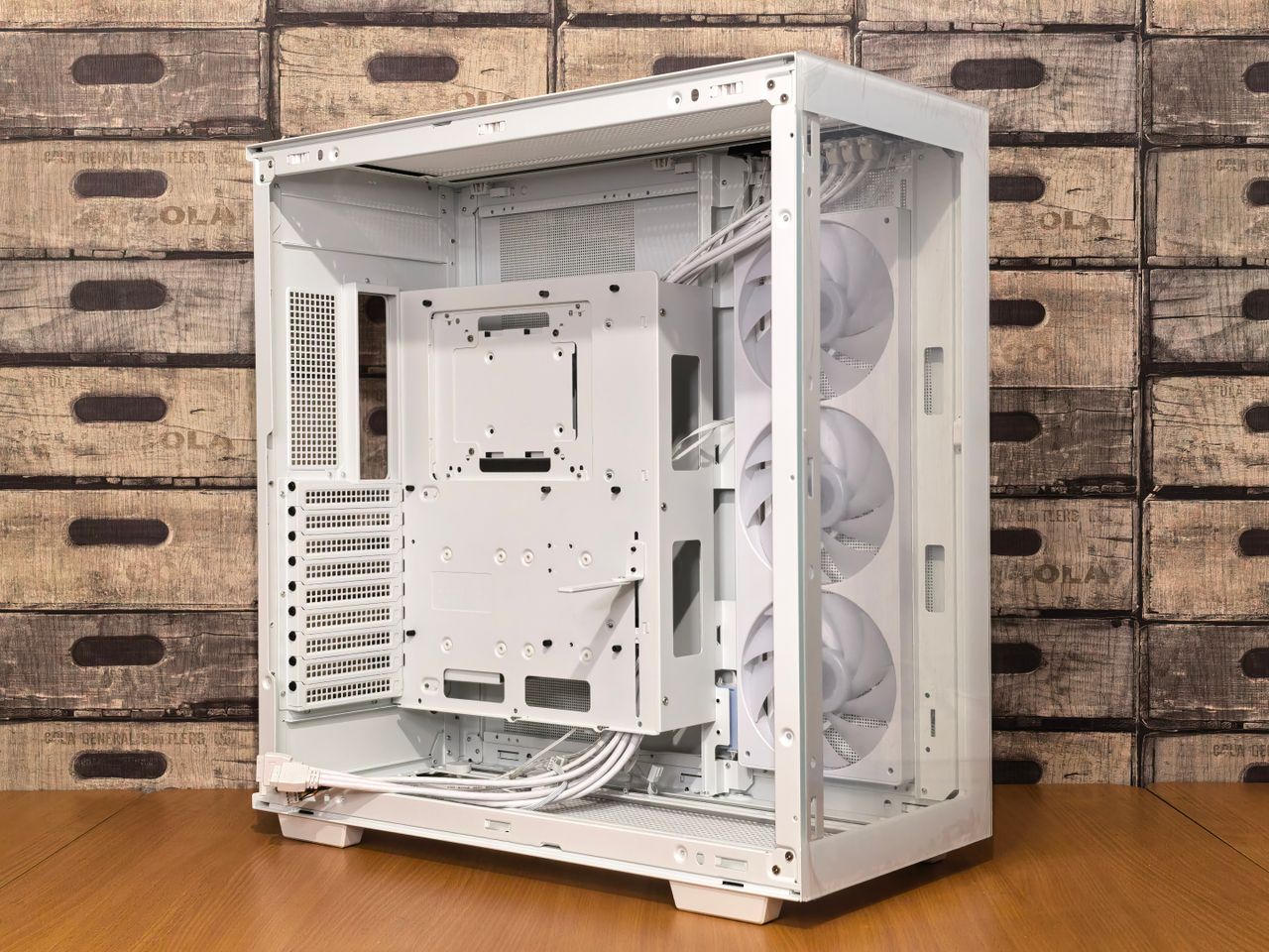 gallery-6 Open sleek white PC case with multiple fans, set against a rustic wooden crate background.