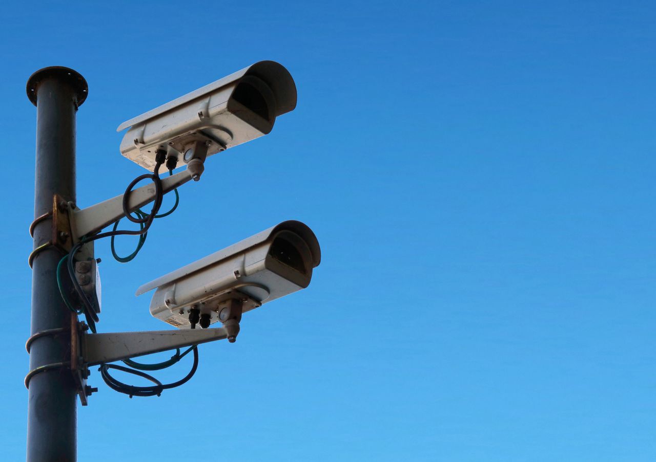 services-img Low angle of security camera attached to black post located isolated on blue sky on sunny day in daytime outside