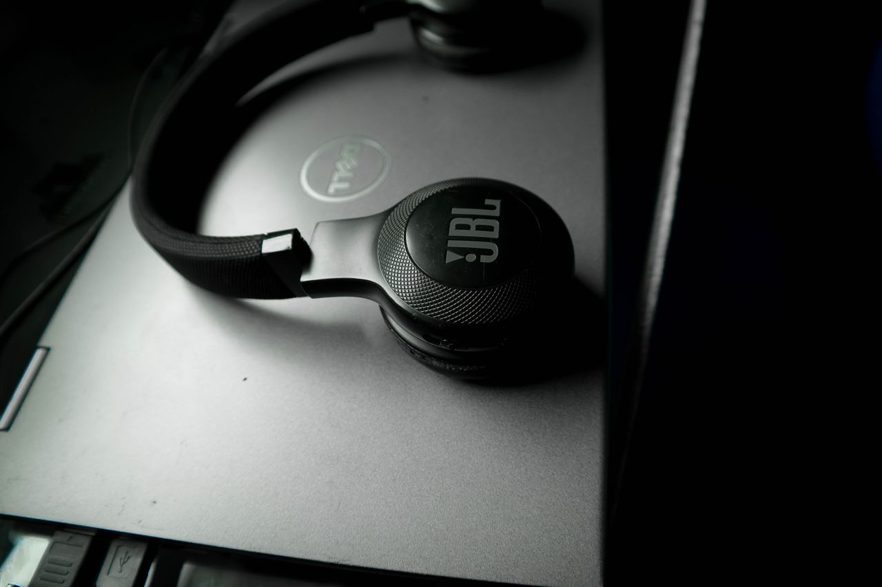 our-services-1 Black JBL wireless headphones resting on a closed Dell laptop, tech essentials for productivity.